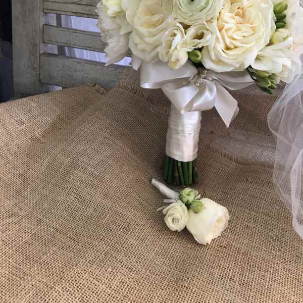 White bridal bouquet with roses and ranunculus, tied with satin ribbon