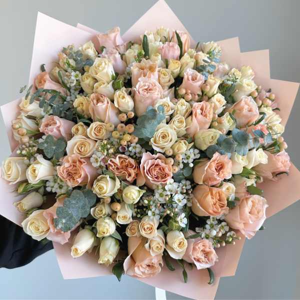 Large bouquet of blush and cream roses wrapped in pale pink paper
