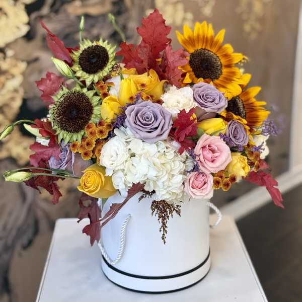 Bouquet of sunflowers, roses, and hydrangeas in a white hatbox