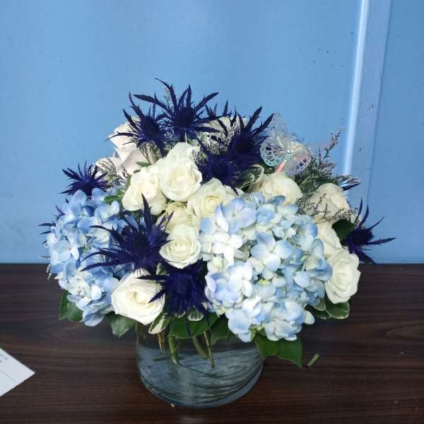 White roses and blue hydrangeas in a glass vase