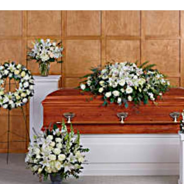 White floral funeral arrangements around a casket