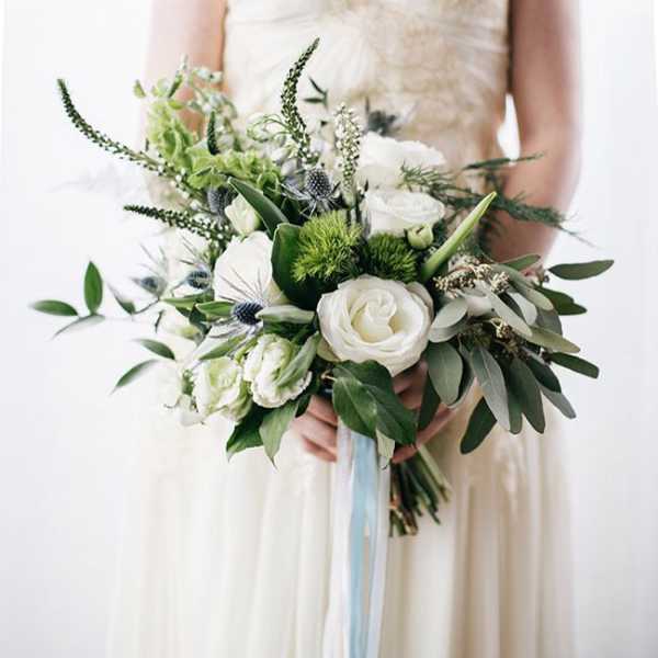 Bride holding a white and green bouquet with ribbon streamers