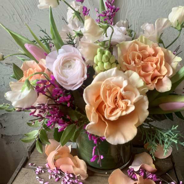 Peach and white roses with pink accents in a glass vase