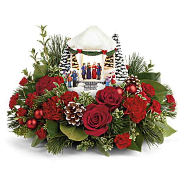 Christmas floral arrangement with red roses and pinecones around a small nativity scene