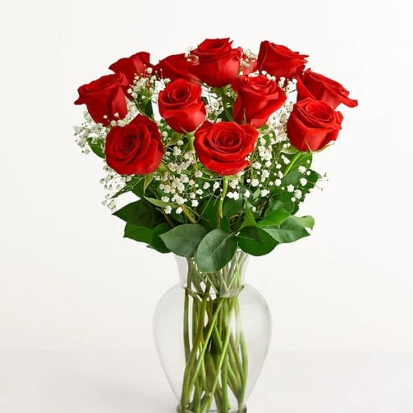 Red roses arranged in a clear glass vase with white baby's breath