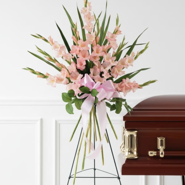 Pink gladiolus standing spray beside a casket