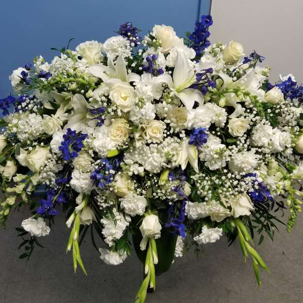 Large white and blue floral arrangement in a dark container