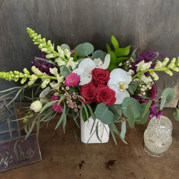 Arrangement of red roses and white orchids in a white vase