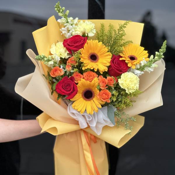 Hand-tied bouquet of red roses, yellow gerberas, and orange spray roses