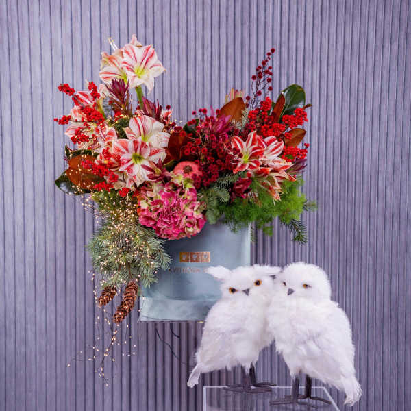 Holiday floral arrangement with red-and-white blooms and two white owl figurines