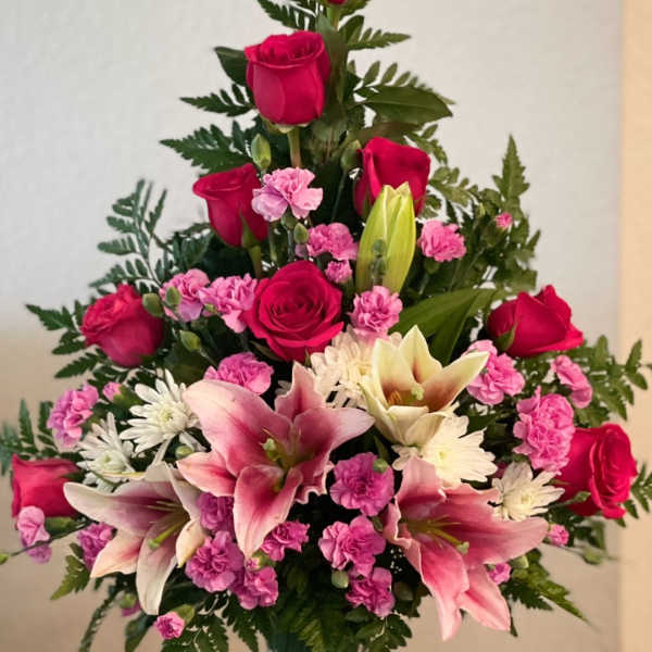 Pink roses and lilies arranged in a clear glass vase