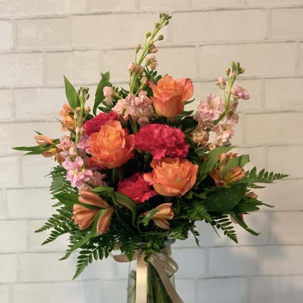 Bouquet of orange roses and pink carnations in a glass vase