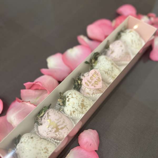 Box of pastel chocolate-covered strawberries with pink rose petals