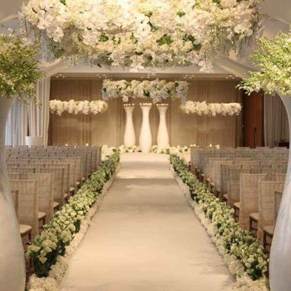 White floral wedding aisle with hanging arrangements and tall pedestal centerpieces