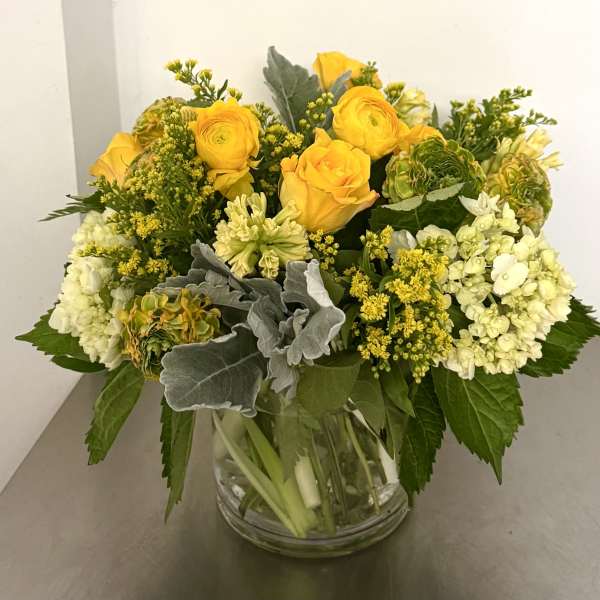 Yellow roses and white hydrangeas arranged in a clear glass vase.