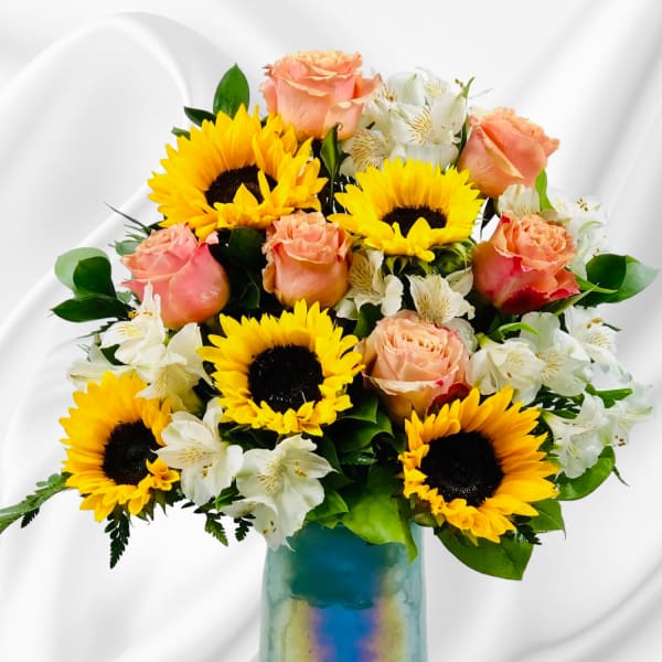 Sunflowers, peach roses, and white alstroemeria in a blue glass vase