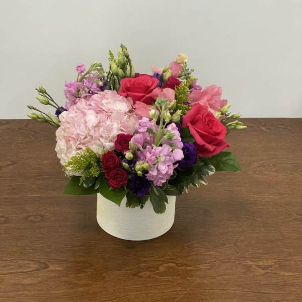 Pink and red flower arrangement in a white box vase