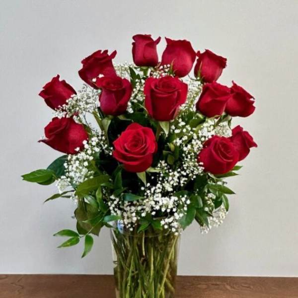 Red roses arranged in a clear glass vase with baby's breath