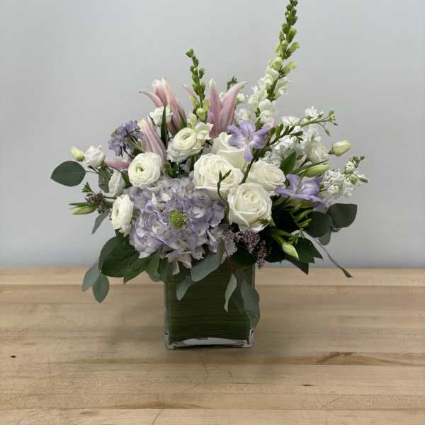 Mixed white and lavender flowers in a square glass vase