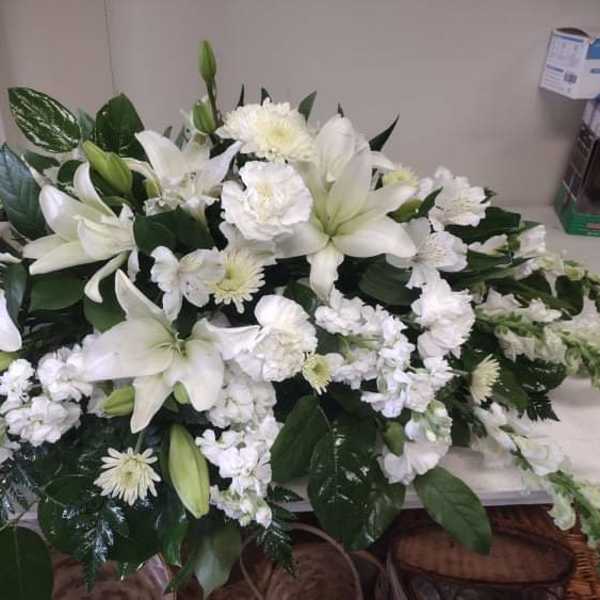 White lilies and chrysanthemums arranged in a low casket spray