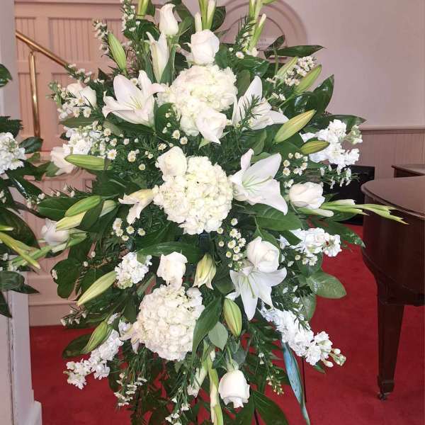 Large white floral standing spray with lilies and roses on an easel