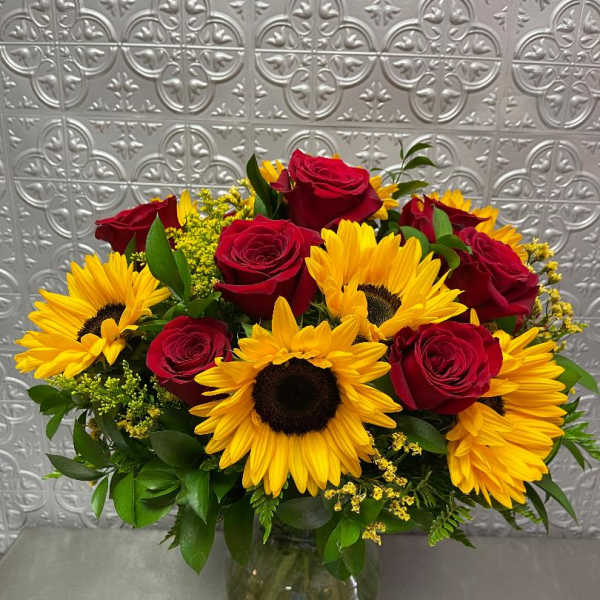 Bouquet of red roses and yellow sunflowers in a glass vase