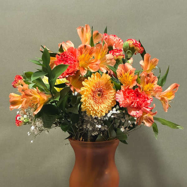 Orange and pink mixed bouquet in a tall frosted vase