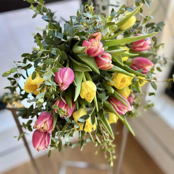 Bouquet of pink and yellow tulips with greenery