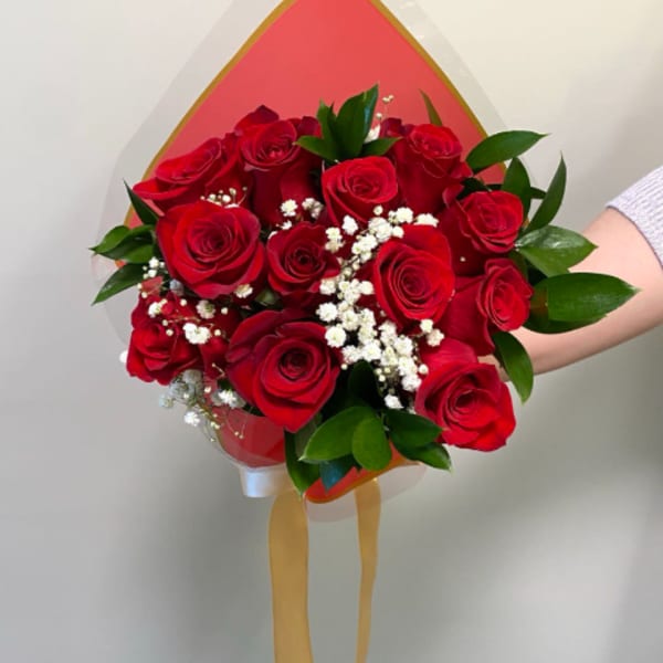 Bouquet of red roses with white baby's breath and green leaves in wrapping