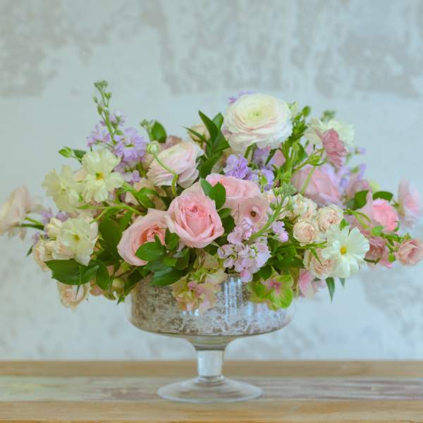 Pink and white floral arrangement in a glass compote vase