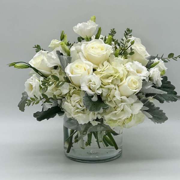 White roses and hydrangeas arranged in a clear glass vase