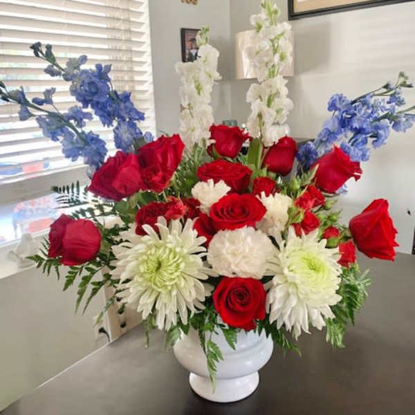 Bouquet of red roses, white chrysanthemums, and blue flowers in a white vase