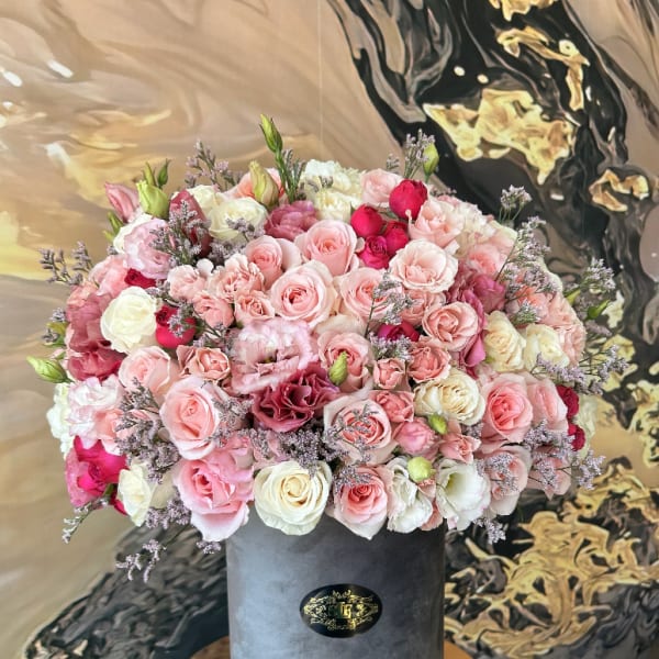 Large pink and white rose arrangement in a gray hatbox