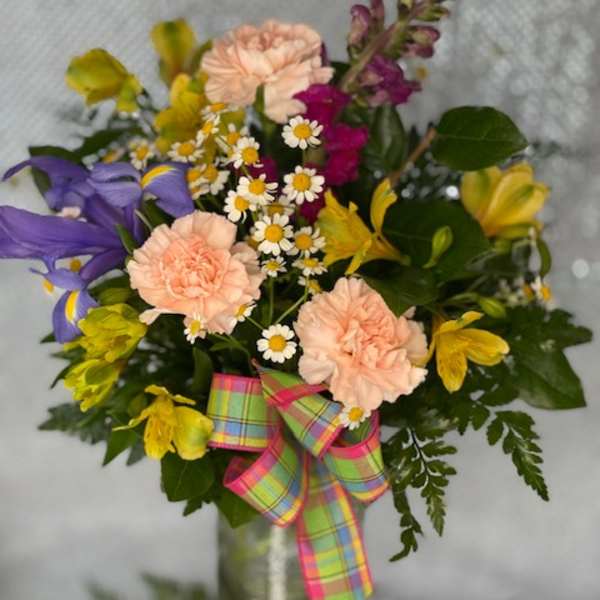 Mixed bouquet with purple lilies, peach carnations, and yellow flowers in a vase
