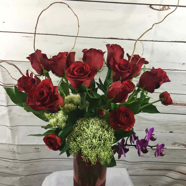 Red roses in a tall vase with purple orchids