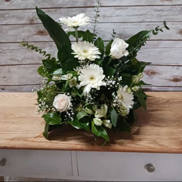White gerbera daisies and roses in a low green arrangement