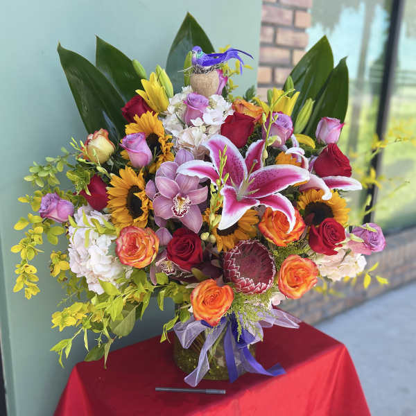 Colorful mixed bouquet with roses, lilies, sunflowers, and orchids in a vase