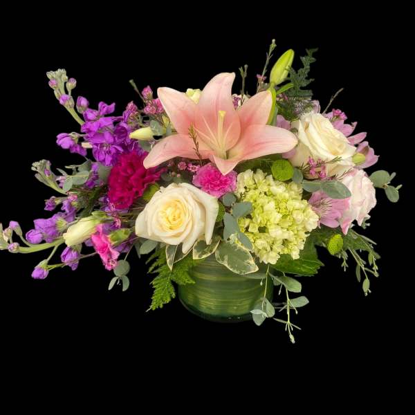 Mixed bouquet with pink lily, white roses, and purple blooms in a green vase