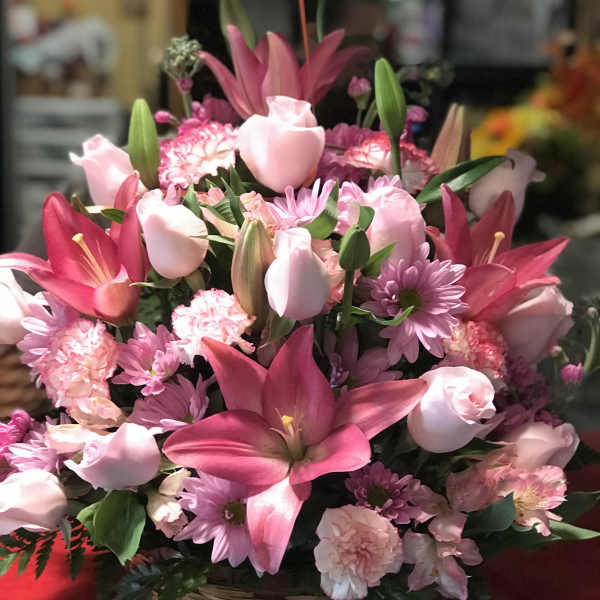 Pink lilies, roses, and carnations in a wicker basket