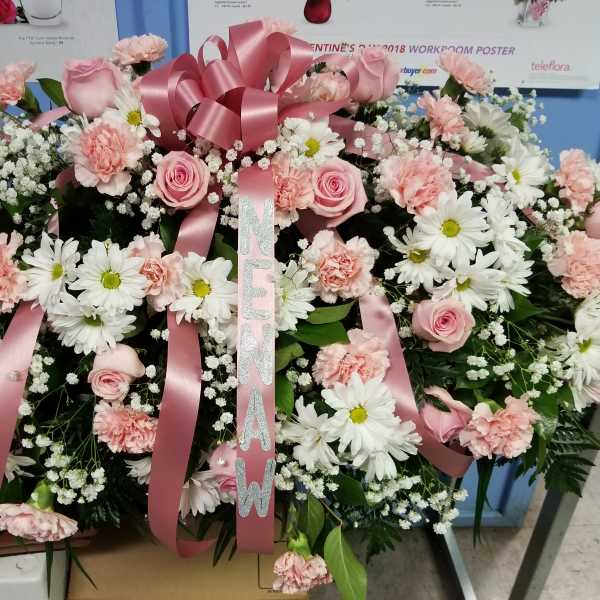 Pink and white funeral spray with roses, carnations, and daisies