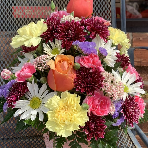 Mixed bouquet in a pink metal bucket with roses, daisies, and carnations