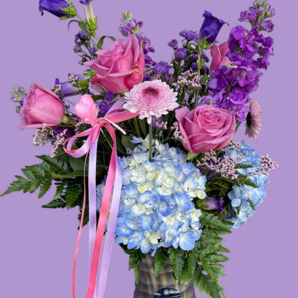 Pink roses and blue hydrangeas in a dark vase with purple flowers