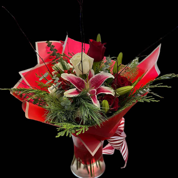 Bouquet of red and white roses with a pink lily in a glass vase