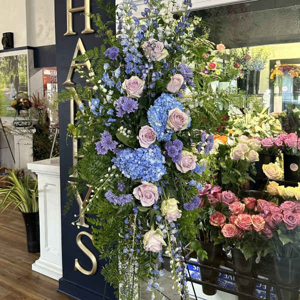 Tall floral standing spray with blue, lavender, and white blooms