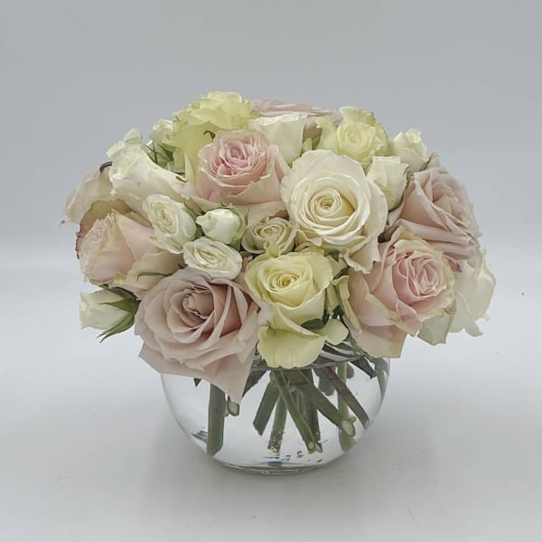 Blush and ivory roses arranged in a clear glass vase