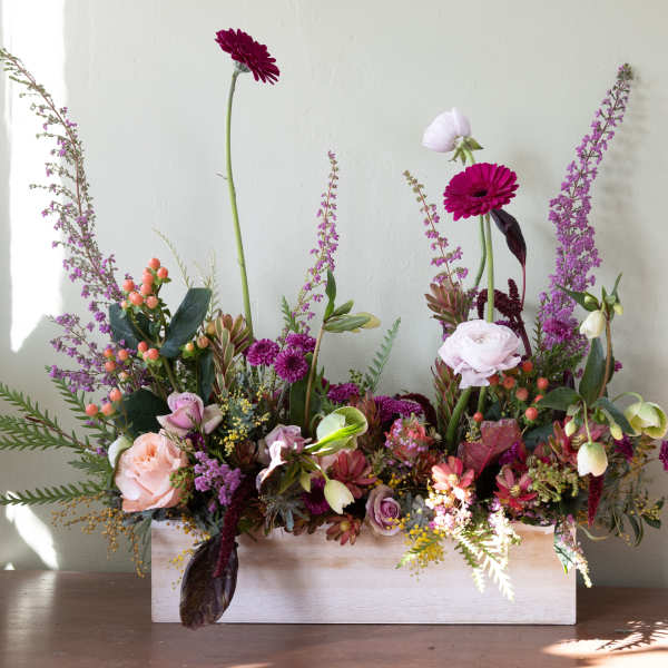 Mixed floral arrangement in a white rectangular box with pink and purple blooms