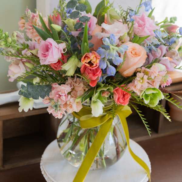 Mixed pastel bouquet in a glass vase with a yellow ribbon