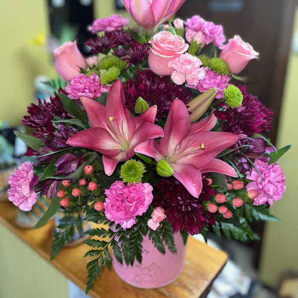 Pink lilies and roses arranged in a pink vase