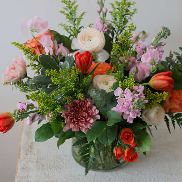 Mixed bouquet of pink, white, and orange flowers in a glass vase