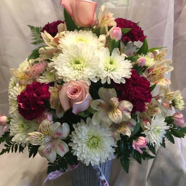 Mixed bouquet in a ribbed vase with pink roses, white mums, and burgundy carnations